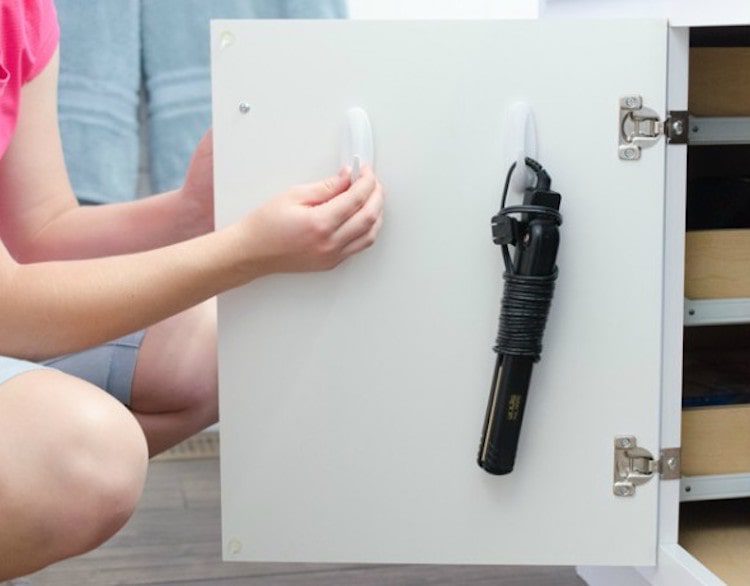 Use some stick on hooks inside a bathroom cabinet door to hang hairdryers, straighteners or curling irons.