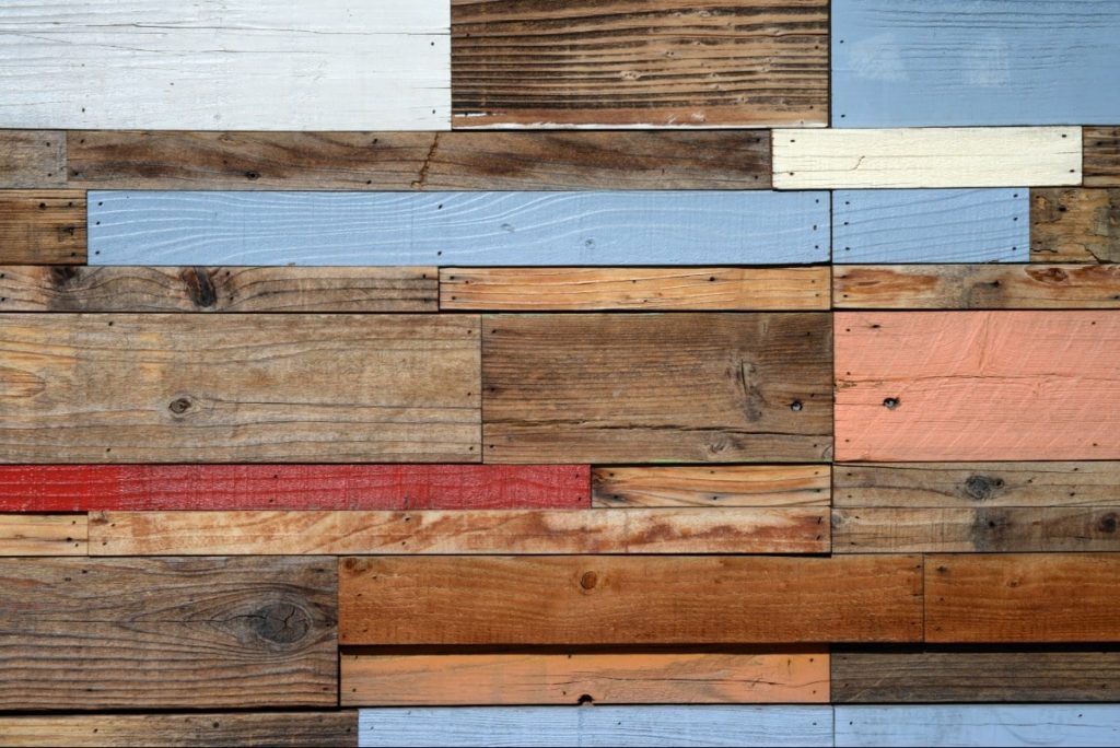 Various pieces of different colored reclaimed wood put together to make wood flooring in an eco-friendly home.