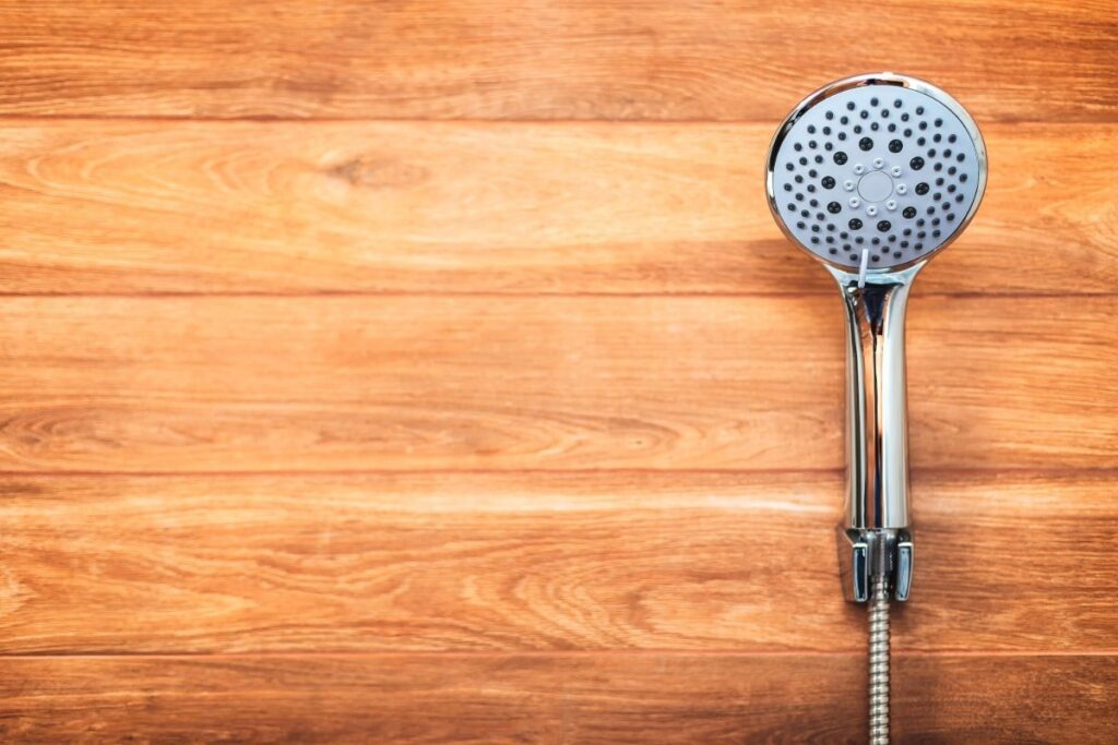 Shower head against a wooden plant wall.