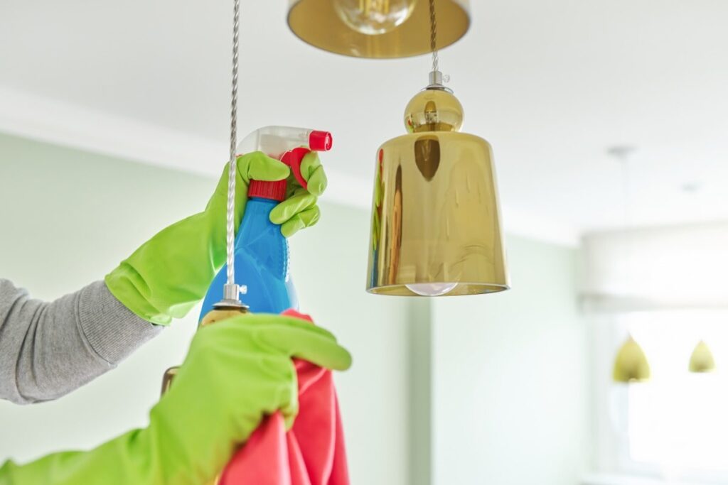 Person is cleaning a chandelier using a spray and cleaning cloth.