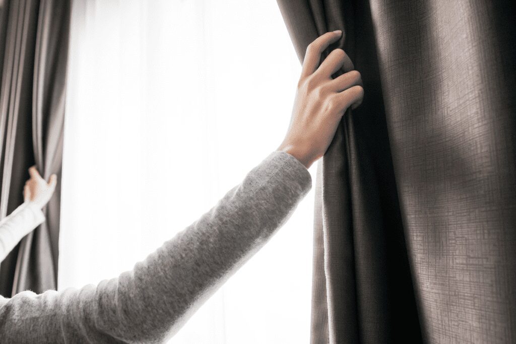 Closeup of woman's hand opening curtain.